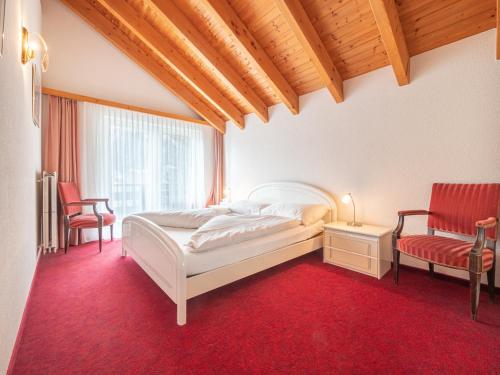 a bedroom with a white bed and a red carpet at Haus Tarbey in Leukerbad