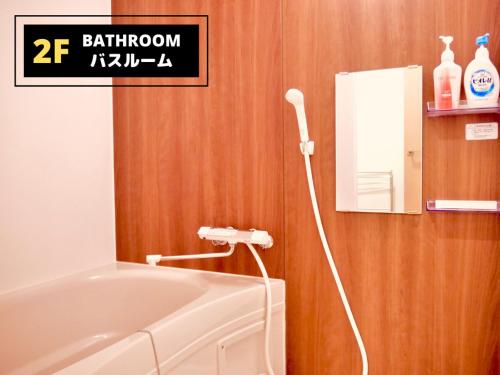 a bathroom with a white bath tub next to a mirror at Jen's House Osaka in Osaka