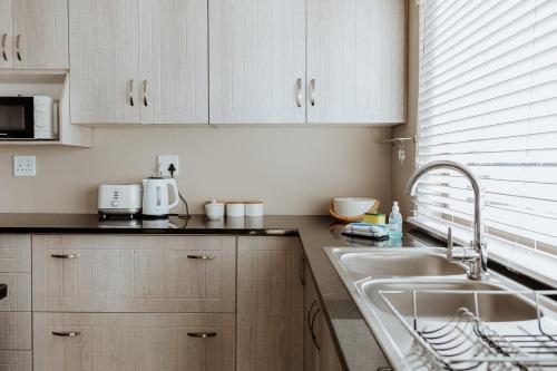 a kitchen with white cabinets and a sink at Roseveldt in Paternoster