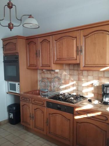 une cuisine avec des armoires en bois et un four à plaques de cuisson dans l'établissement La Sente , Le Rendez-vous, à Mont-Dol