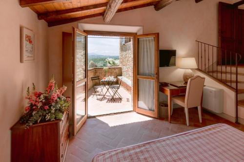 ein Schlafzimmer mit einem Schreibtisch und ein Zimmer mit einem Balkon in der Unterkunft Borgo Sant'Ambrogio - Resort in Pienza