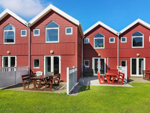 um edifício vermelho com uma mesa de piquenique e bancos em 6 person holiday home in Hadsund em Hadsund