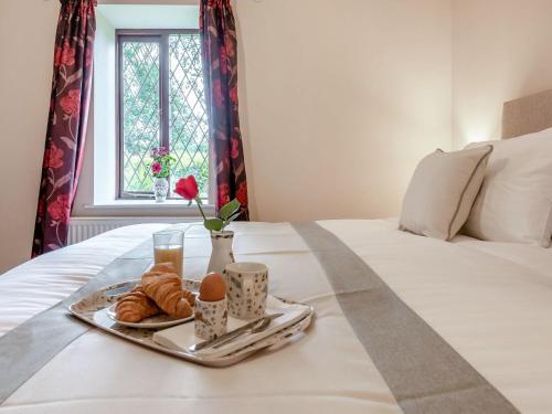 a tray of croissants and eggs on a bed at Llanfair Hill Cottage in Cwrt-newydd