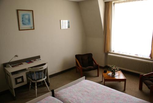 a bedroom with a bed and a desk and a window at Hotel Domstad in Utrecht