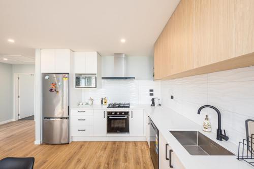 a kitchen with white cabinets and a stainless steel refrigerator at 37 Galaxy B in Lake Tekapo