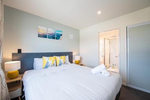 a bedroom with a large white bed with yellow pillows at 37 Galaxy B in Lake Tekapo