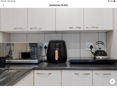 a kitchen counter with a coffee maker and a microwave at Rueby’s Apartment 101 in Dullstroom
