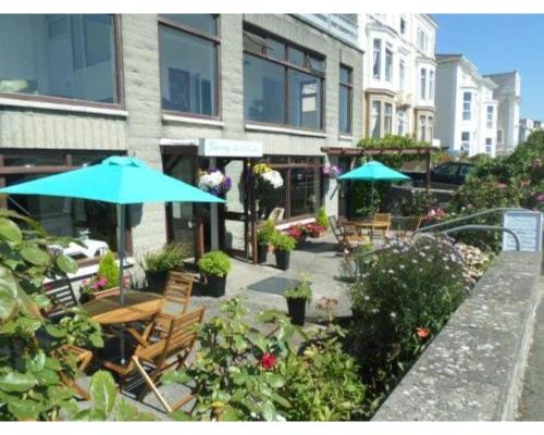 a patio with tables and umbrellas in front of a building at Savoy B&B in Weston-super-Mare