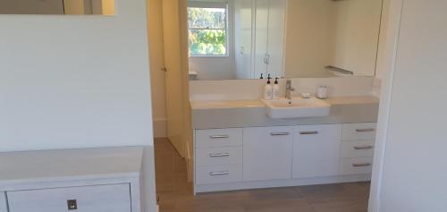 a white bathroom with a sink and a mirror at Pandanus Coolum Beach in Coolum Beach