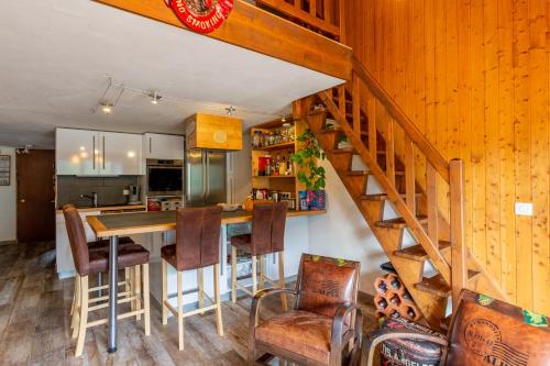 une cuisine avec un escalier, une table et des chaises dans l'établissement Le Beauregard, au Grand-Bornand