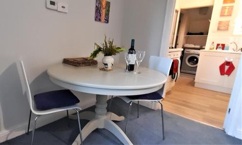 a white table with a bottle of wine and two glasses at Garden Cottage, Five Pines in Acton Turville