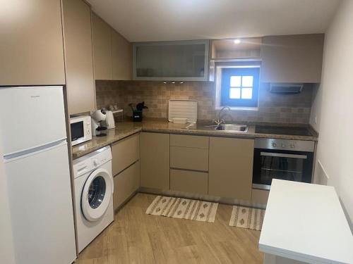 a kitchen with a washer and dryer and a window at Casa do Calhau - AL in Hombres