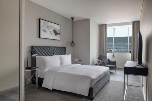 ドーハにあるSteigenberger Residence Dohaの白いベッドと椅子が備わるホテルルームです。