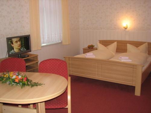 a hotel room with two beds and a table and a television at Hotel Garni Dekorahaus in Bad Schandau