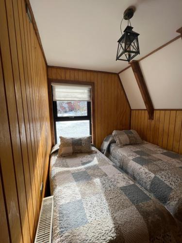 a bedroom with two beds and a window at CABAÑAS BOSQUE NEVADO in Malalcahuello