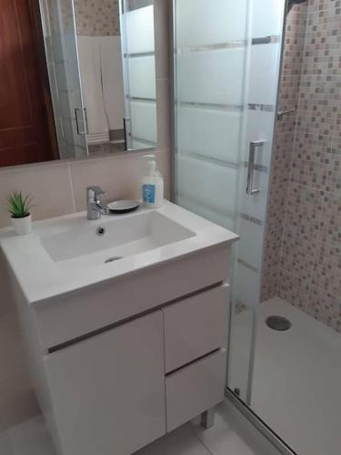 a white bathroom with a sink and a shower at Apartamento Batalha - Quarteira, Algarve, Portugal in Quarteira