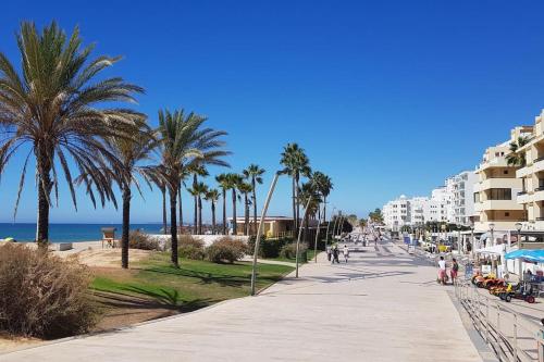 a street with palm trees and buildings on the beach at Apartamento Batalha - Quarteira, Algarve, Portugal in Quarteira