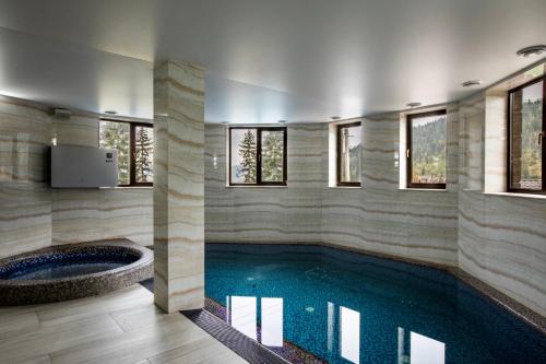 una piscina con bañera en una habitación con ventanas en Mardan Palace SPA Resort en Bukovel