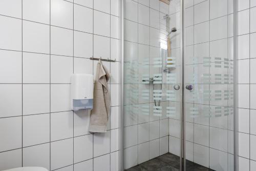 a white tiled bathroom with a shower and a toilet at Mikkelparken Ferietun in Kinsarvik