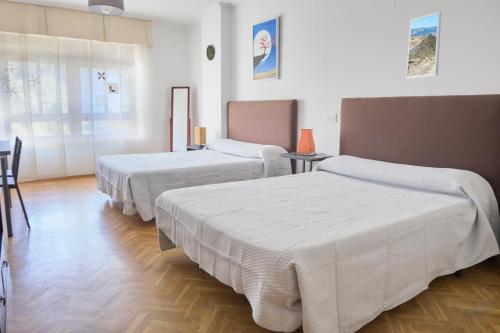 a hotel room with three beds and a table at Alojamiento Particular in Almería