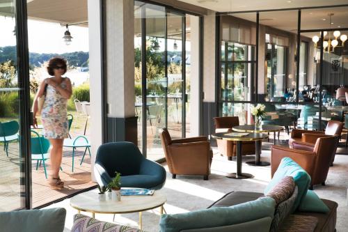 a woman standing in the lobby of a restaurant at Best Western Plus Hotel les Rives du Ter in Larmor-Plage