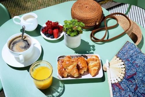 a table with a plate of pastries and a cup of coffee at Best Western Plus Hotel les Rives du Ter in Larmor-Plage
