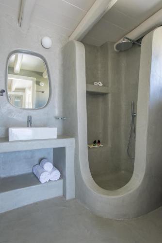 a bathroom with a sink and a shower with a mirror at Yialos Ios Hotel in Ios Chora