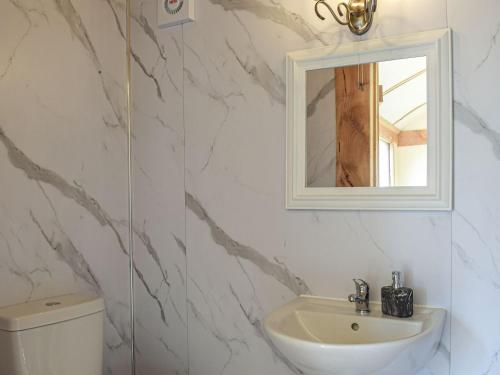 a bathroom with a sink and a mirror and a toilet at The Sawyers Hut-uk39775 in Trefeglwys