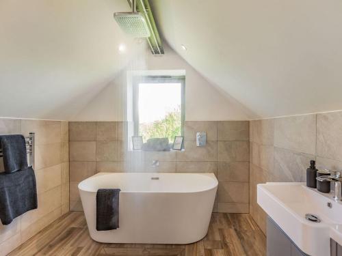 uma casa de banho com uma banheira branca e um lavatório. em Russets em North Weald