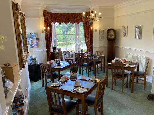 a dining room with tables and chairs and a clock at Maple Bank Country Guest House in Keswick