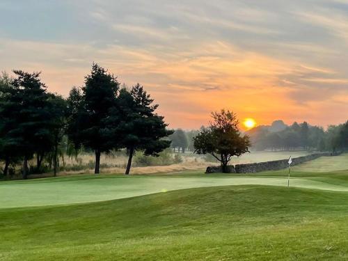 una puesta de sol en un campo de golf con un green en Horsley Lodge, en Derby