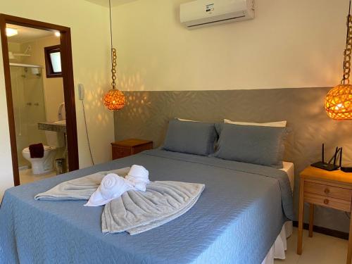 Un dormitorio con una cama azul con una toalla. en Villas do Pratagy Jambo I com Jacuzzy en Maceió