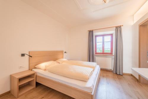 Un dormitorio con una cama grande y una ventana en Glögglhof, en Appiano sulla Strada del Vino