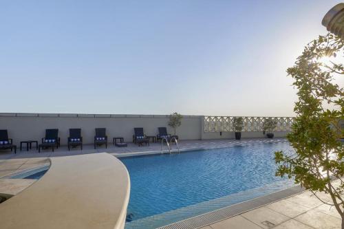 a large swimming pool with blue chairs in a building at Safir Hotel Doha in Doha