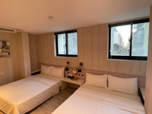 two beds in a room with two windows at Sunrise Hotel in Taipei