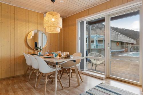 a dining room with a table and chairs and a large window at Mikkelparken Ferietun in Kinsarvik