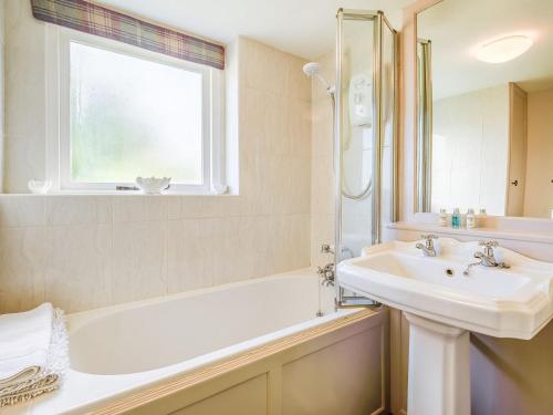 a bathroom with a sink and a bath tub and a window at Bimble Cottage in Ingham