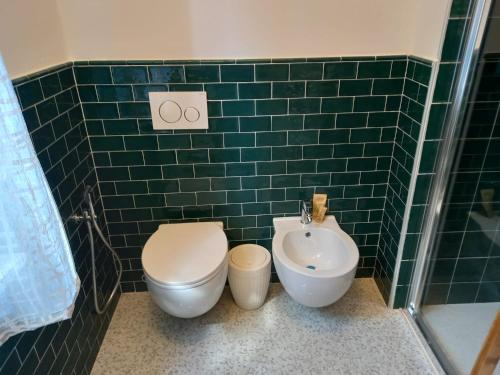 a green tiled bathroom with a toilet and a sink at Mercante In Fiera in Verona
