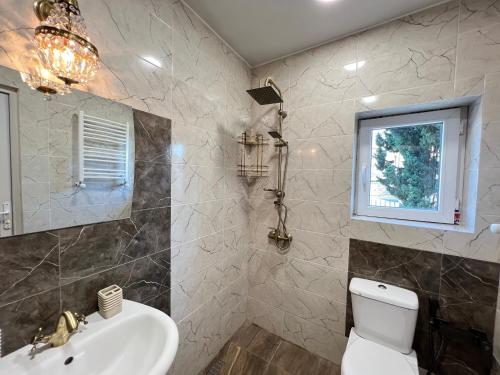 een badkamer met een wastafel, een toilet en een raam bij Lola Apartments in Tbilisi City