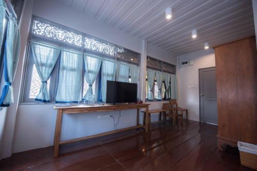 a room with a desk with a television and windows at DONPIN8-Timeless House Chiang Mai in Chiang Mai