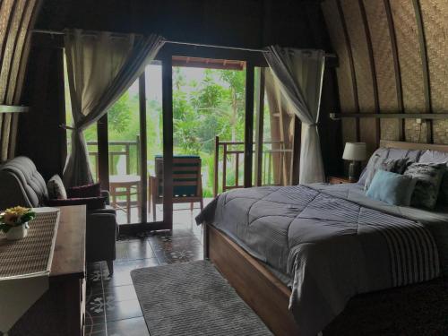 1 dormitorio con cama, sofá y ventana en The Green ujung Villa en Ujung