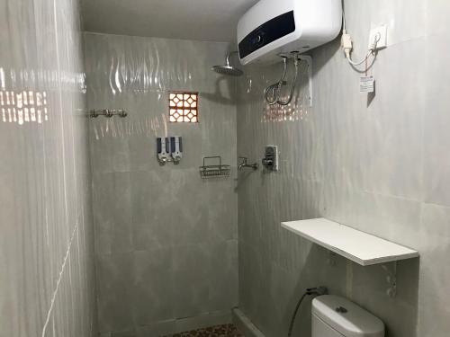 baño con ducha y aseo y ventana en The Green ujung Villa en Ujung