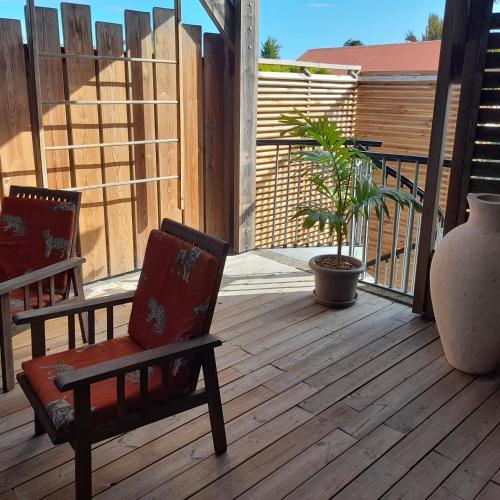 eine Veranda mit zwei Stühlen und einer Pflanze auf einem Deck in der Unterkunft A 3 mn à pied du lagon... Chambre Cardinal in L'Étang-Salé-les-Bains