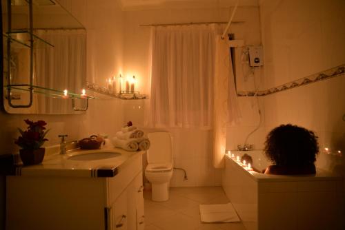 a woman in a bathroom with a sink and a toilet at Royal Victoria House in Kampala