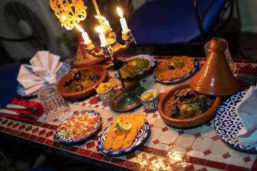 a table topped with plates of food and candles at Maison Adam in Fès