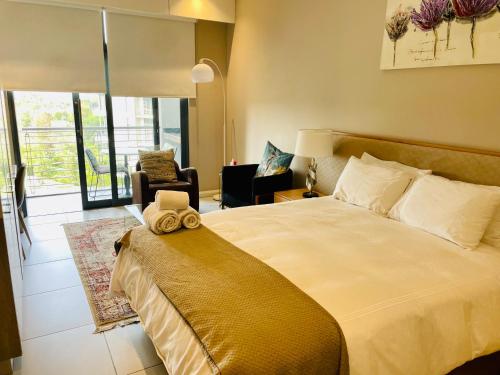 a bedroom with a large bed and a living room at Menlyn Maine Trilogy Hotel in Pretoria