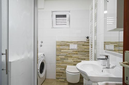 Baño blanco con lavabo y aseo en Apartment Bojic, en Vodice