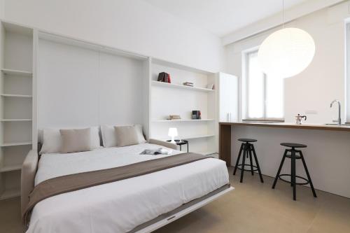 ein weißes Schlafzimmer mit einem großen Bett und einer Küche in der Unterkunft Contempora Apartments - Cermenate 54B in Mailand