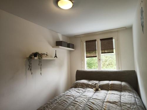un animal de peluche sentado en una cama en un dormitorio en habitación en piso compartido en Yverdon-les-Bains