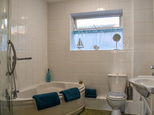 a bathroom with a tub and a toilet and a sink at Farriers in Bransgore